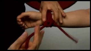 Simple wrist cuff tutorial showing hands demonstrating knot tying techniques with red rope