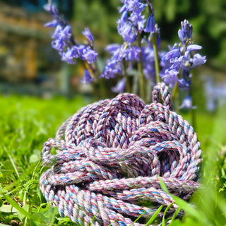 Bamboo bondage rope lilac coiled among purple flowers in a vibrant green garden